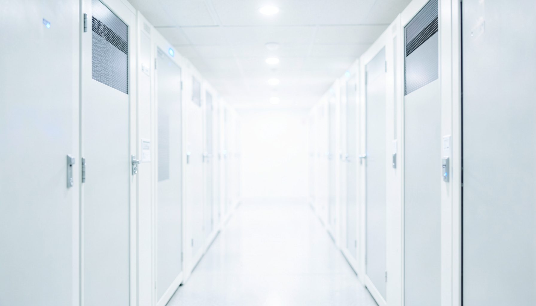 Bright, high-key photograph of a server-room corridor with subtle blue indicator lights, conveying enterprise infrastructure in a clean, uncluttered composition.